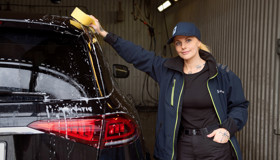 Bilvård på Lindskrog parkering: en kvinna handtvättar omsorgsfullt en parkeringskunds bil.