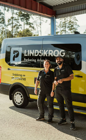 Trevlig personal framför en transferbuss märkt ”Lindskrog Parkering Arlanda”.